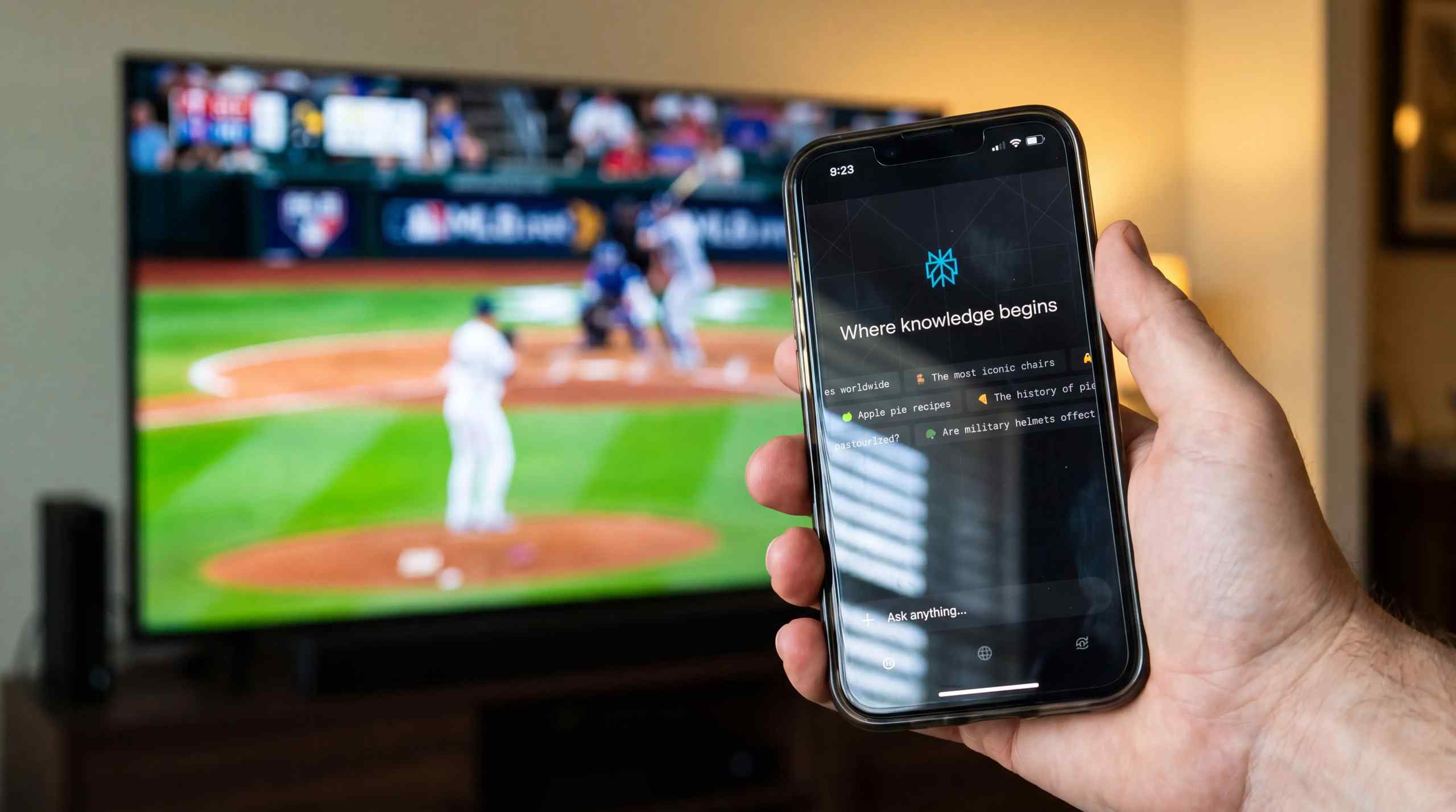 A baseball game on a TV in the background with a smartphone running Perplexity AI in the forefront.